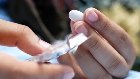 primer plano de una mano tomando una píldora blanca de un paquete de ampollas