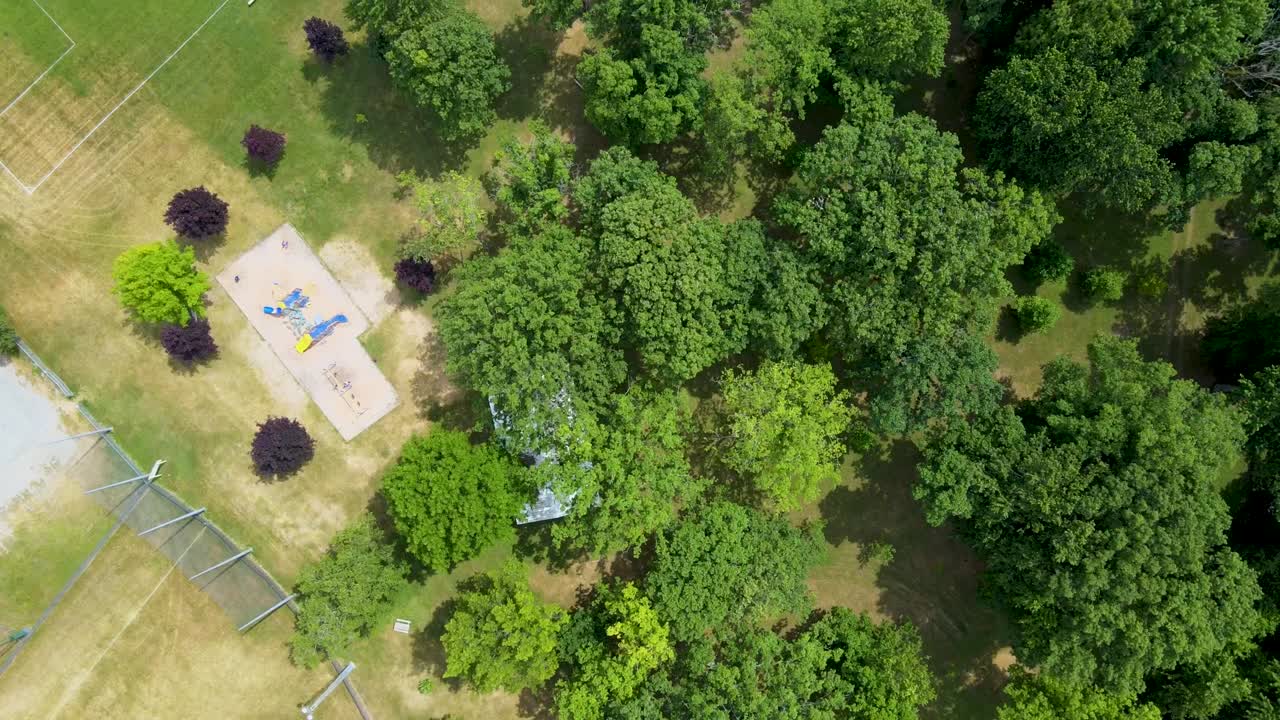 vista aérea de arriba hacia abajo de un campo de fútbol y un patio de recreo cerca de un bosque en la pequeña ciudad de mount bridges