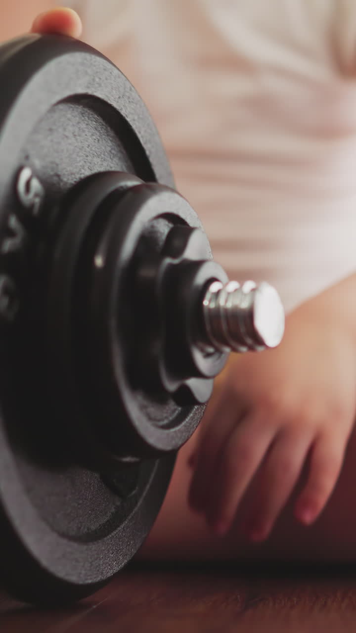 Little boy fixes gear detail near plate on heavy barbell with hand. Motivated toddler prepares equipment for workout in gym closeup slow motion