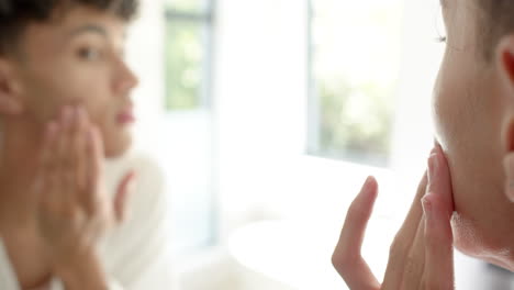 applying skincare, person looking in mirror, focusing on self-care routine