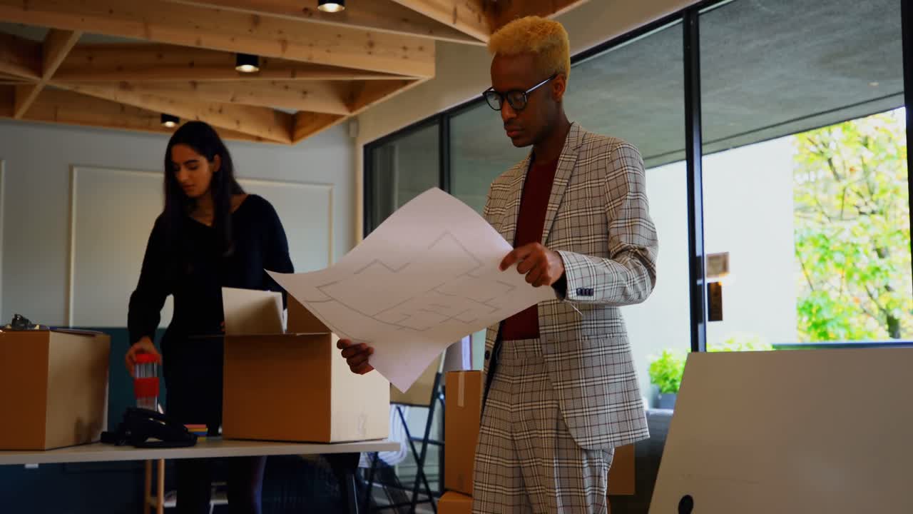Young black businessman looking at blueprint in modern office 4k