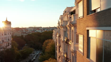 Elevated-forwards-fly-along-row-of-buildings-in-city-centre.--Old-palace-with-decorated-facade-illuminated-by-bright-setting-sun.