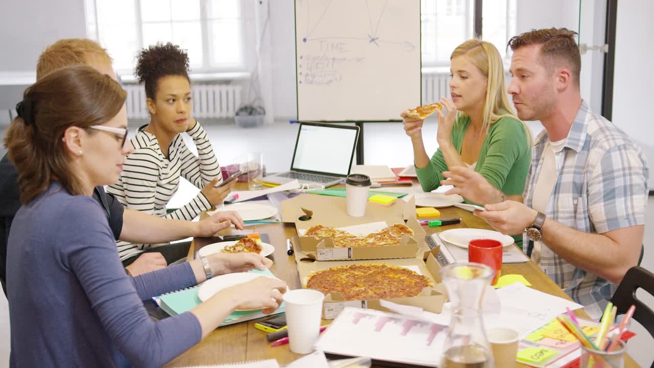 Giovani che si godono la pizza in ufficio