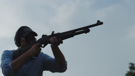 low-angle of man firing pump-action shotgun