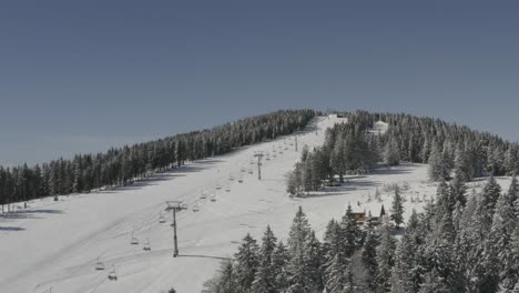 ski lift and main downhill track at kope ski resort slovenia, aerial orbit left reveal shot