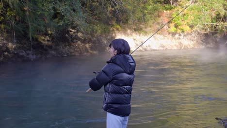 slow motion of a woman throws a spinning rod for fishing in a forest river