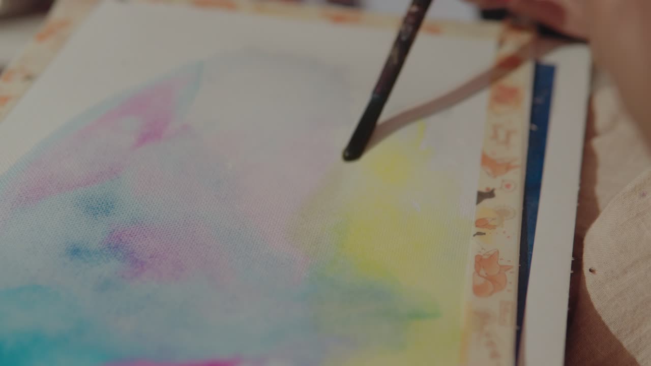 화려한 스트로크를 만들기 위해 브러쉬를 사용하는 손을 보여주는 진행 중인 수채화 그림의 클로즈업