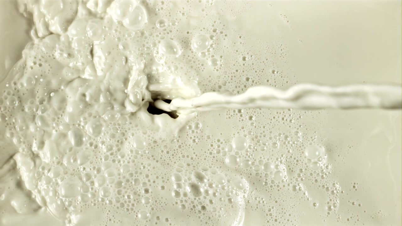 Getto di latte che si versa e schizza con bolle al rallentatore.