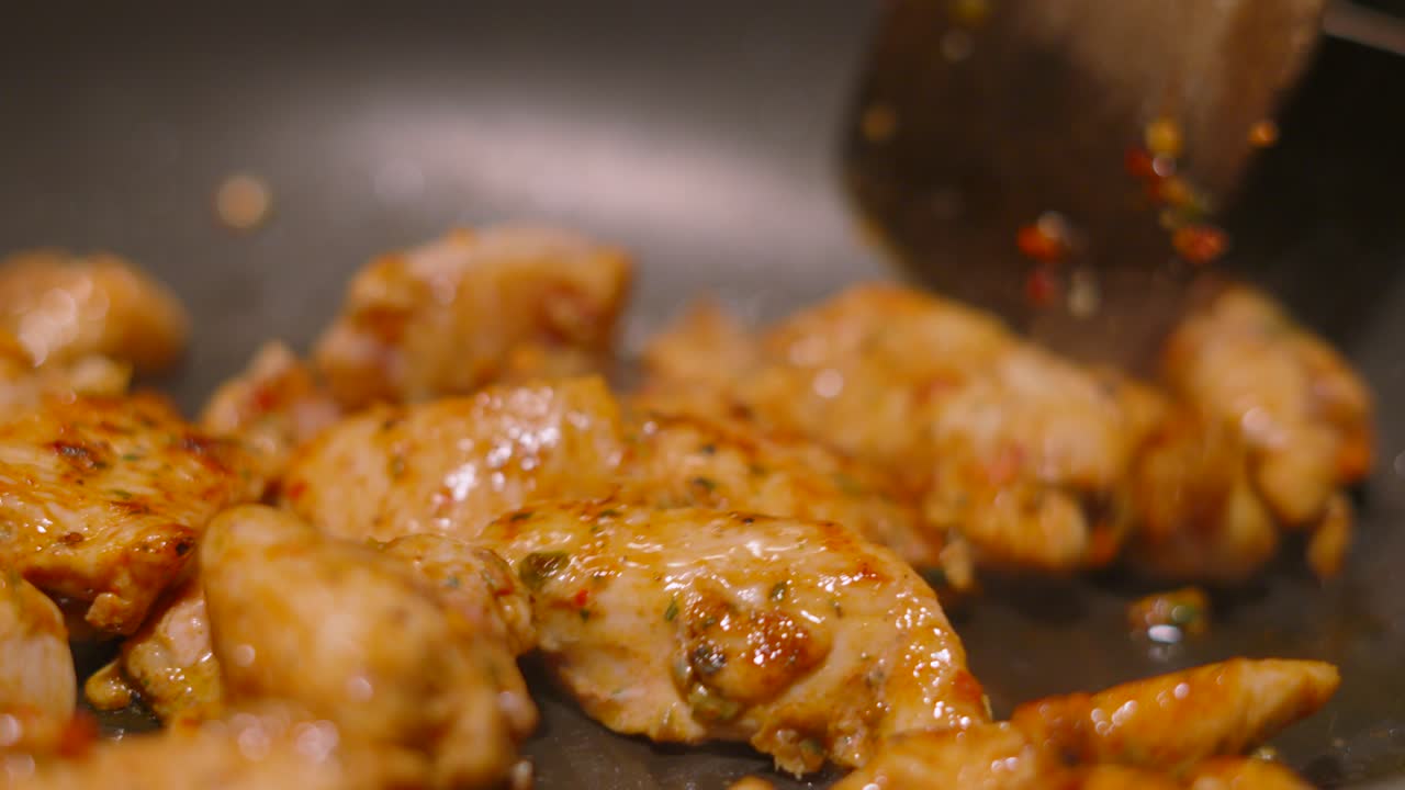 Close Up of Marinated Chicken Pieces Cooking in Wok Pan with Chinese Spices Coating Outside for Great Flavour as Wooden Spatula Moves Food Around Pan. Oriental Style Dish.