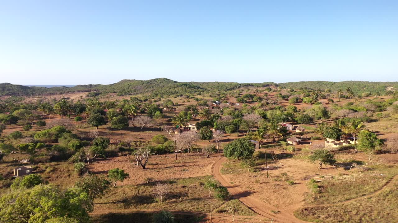 Toma cinematográfica aérea descendente del pueblo de Chidenguele mostrando chozas africanas tradicionales y plantaciones