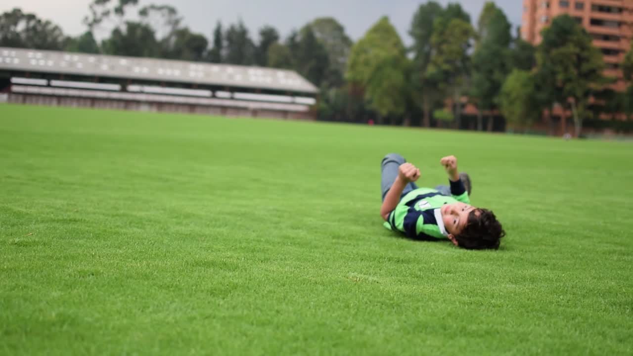 어린 소년이 풀밭에서 굴러다니며 놀고 있다