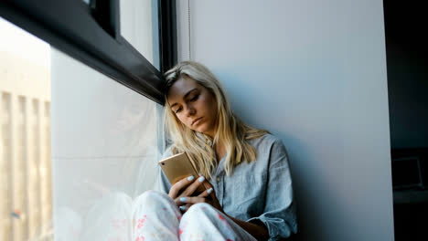 Worried-woman-using-mobile-phone-near-window-4k