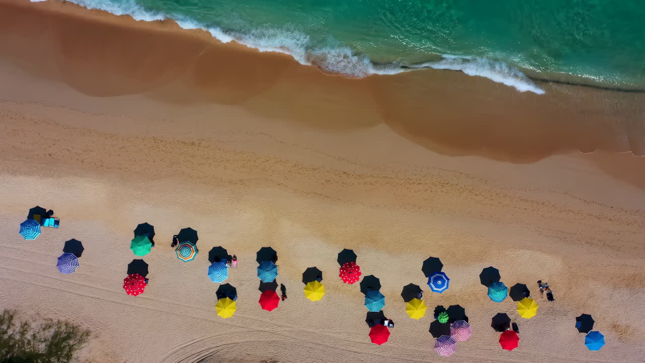 Aerial View of Colorful Umbrellas on a Tropical Beach with Ocean Waves