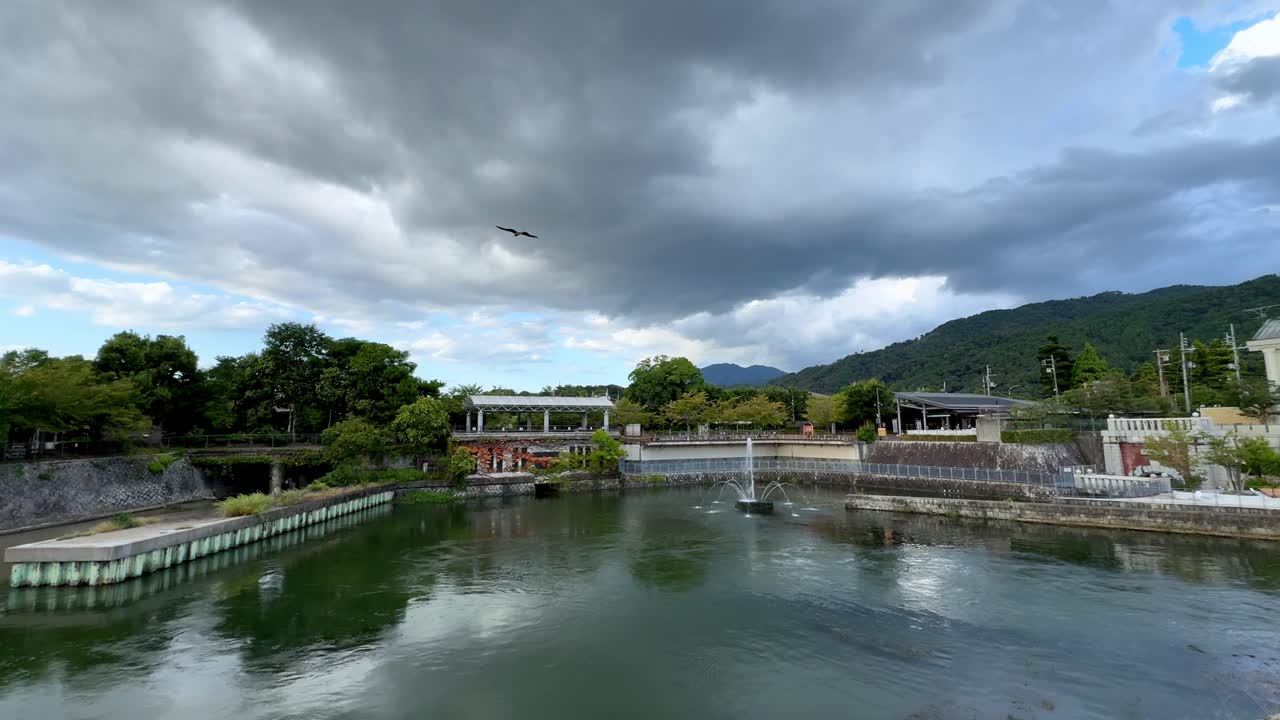 Serene Kyoto riverside under dramatic cloudy sky in Japan
