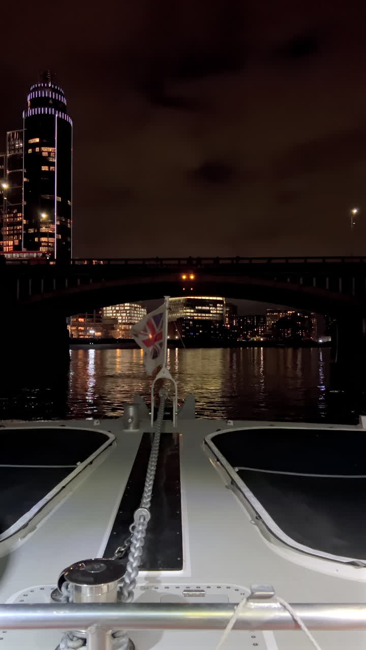 The flag of the United Kingdom waving on a boat moving on the Thames River in the evening in London, England. Vertical