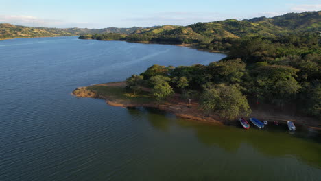 Aerial-flyover-Presa-de-Tavera-artificial-lake-during-golden-sunset-in-Santiago-de-los-Caballeros,-Dominican-Republic