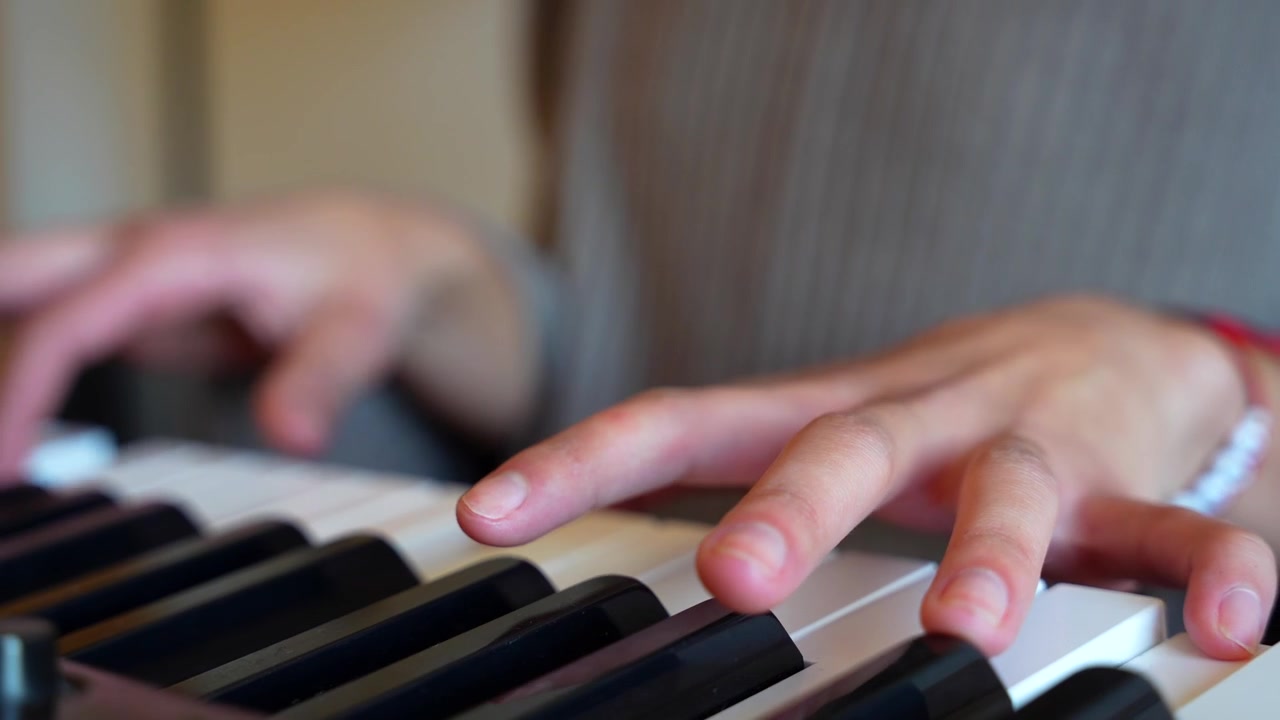 Naisen kädet soittamassa kaunista melodiaa pianolla viihtyisässä kotiympäristössä, esitellen musiikillista lahjakkuutta.