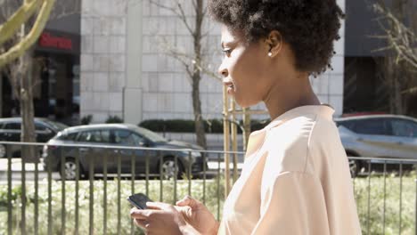 side view of calm young woman texting on smartphone