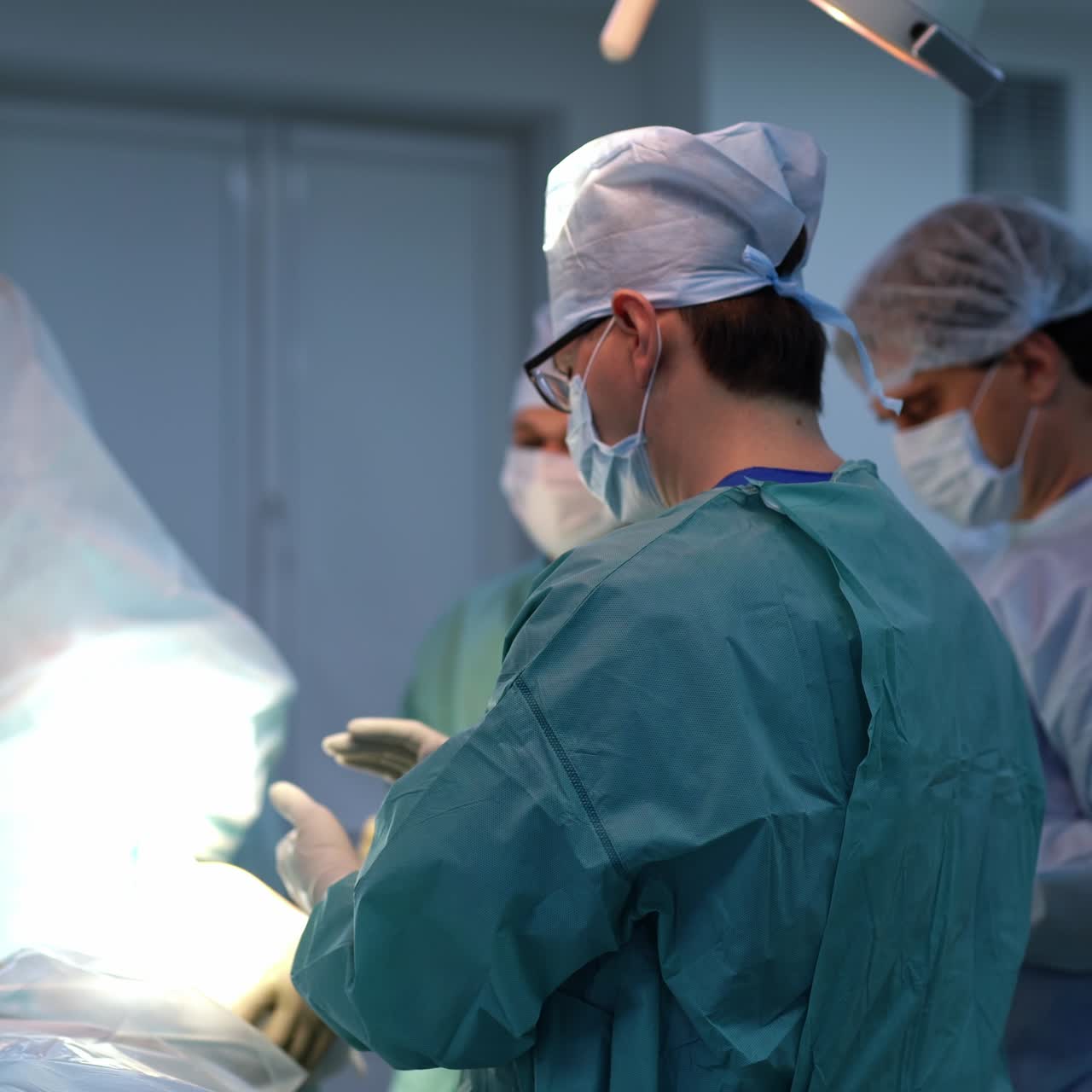 Three male surgeons preparing for operation. Professionals apply antiseptic on their gloved hands standing at operational table