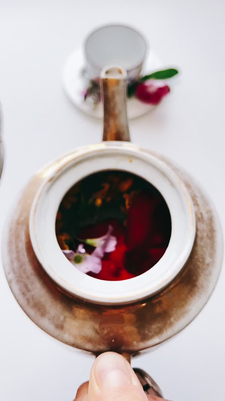 Hand holding a vintage teapot with flowers