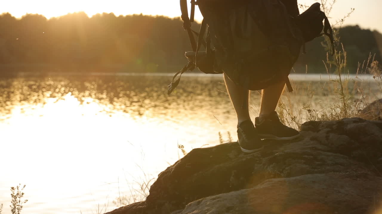 Hiker Rising On A Hill. Man with a backpack rises to the top of the hill