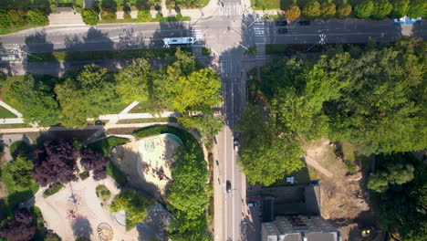 toma aérea de arriba hacia abajo del tráfico en la carretera en la ciudad polaca llamada gdynia en el área suburbana con árboles del parque