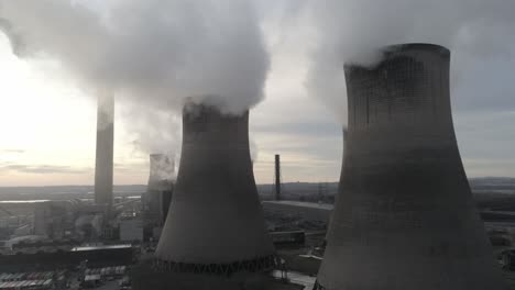 aerial view rising to uk power station cooling towers atmospheric smoke steam emissions at sunrise