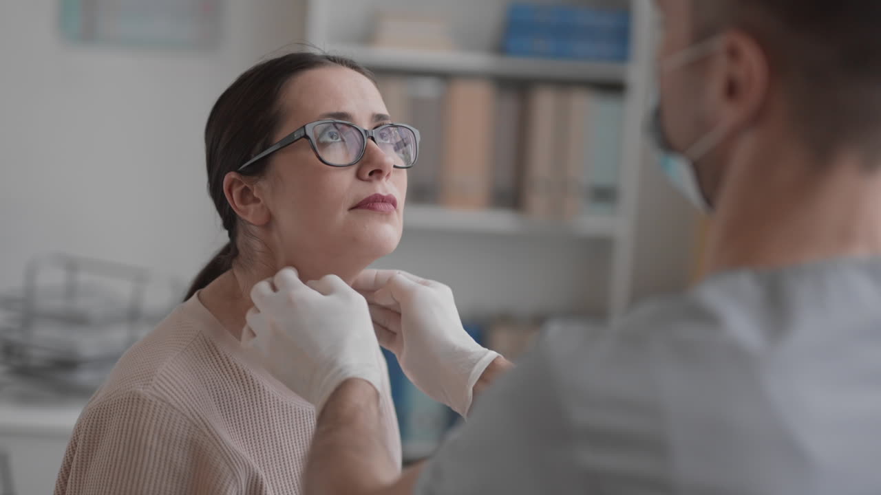 médico palpatando el cuello de una mujer caucásica