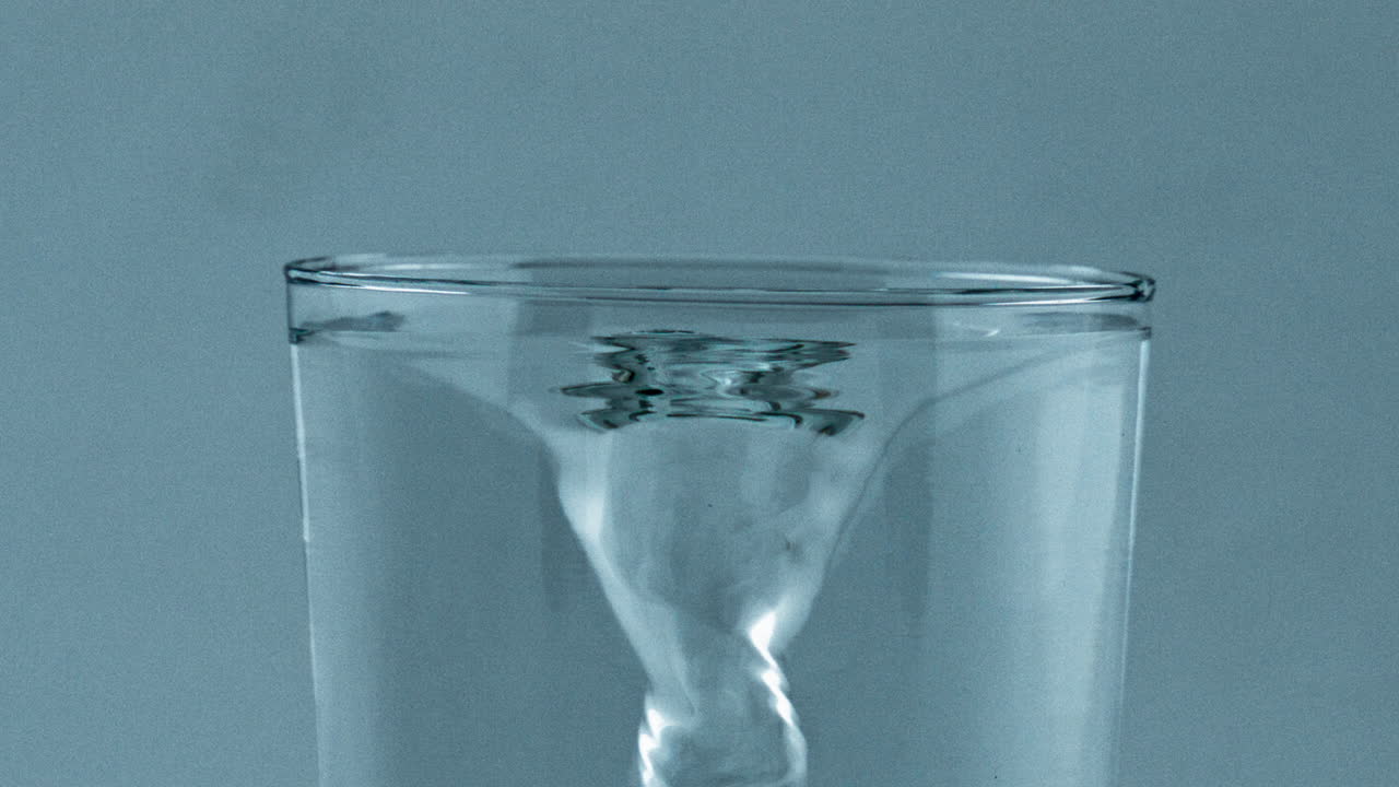 Spinning fresh water vessel closeup. Transparent aqua created funnel glassware