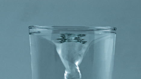 spinning fresh water vessel closeup. transparent aqua created funnel glassware