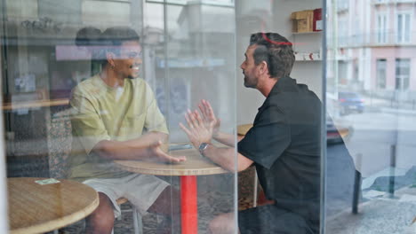 pareja masculina comunicación amistosa en un pequeño café. dos hombres hablando en una reunión