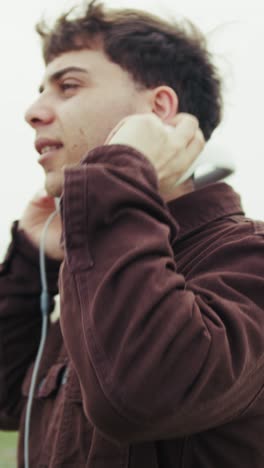 man feeling free while listening to music on the shore during winter