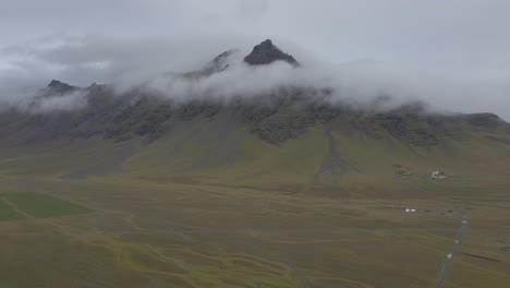 verdant and flat icelandic landscape with mountains shrouded low clouds, iceland
