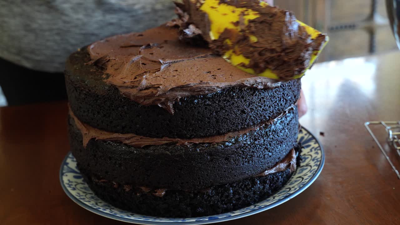 Spalmare la glassa al cioccolato sulla parte superiore di una torta a tre strati