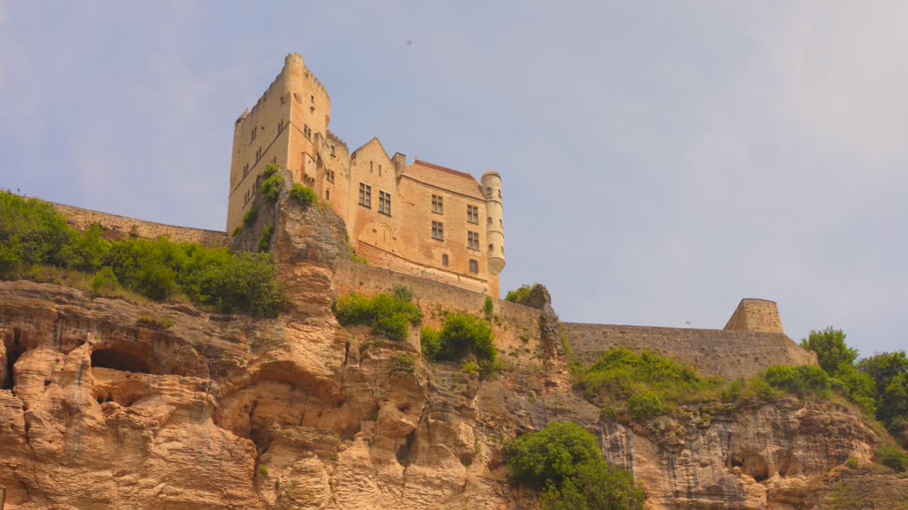 A low-angle shot of the majestic Beynac Castle towering above the cliffs