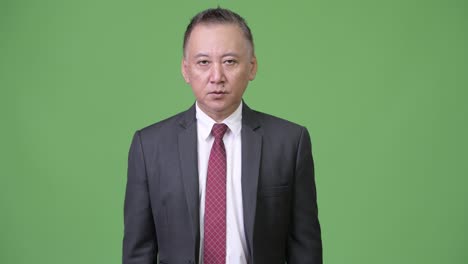 입술에 손가락을 은 성숙한 분노한 일본 사업가