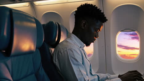 man on an airplane admiring the sunset through the window