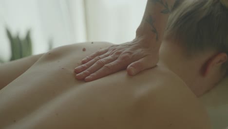 person receiving a relaxing back massage in a calm, light-filled room, close-up shot