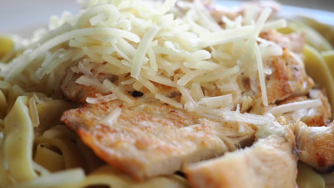 Primo piano di pollo alla griglia con pasta e formaggio grattugiato