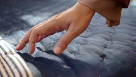 a close-up of a person's hand touching a quilted blue fabric