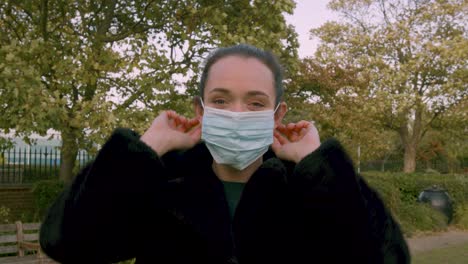 Female-smiling-at-camera-putting-on-medial-facemask