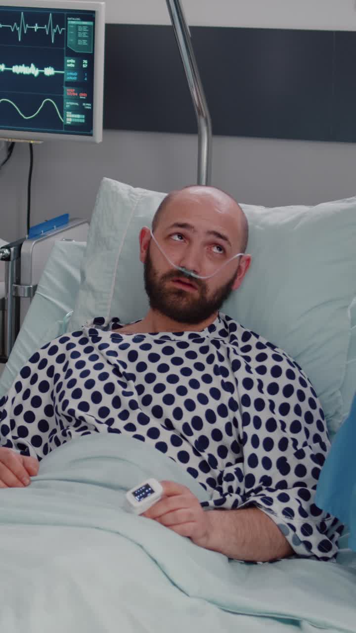 Video verticale: uomo malato a riposo nel letto con un tubo dell'ossigeno che spiega i sintomi della malattia