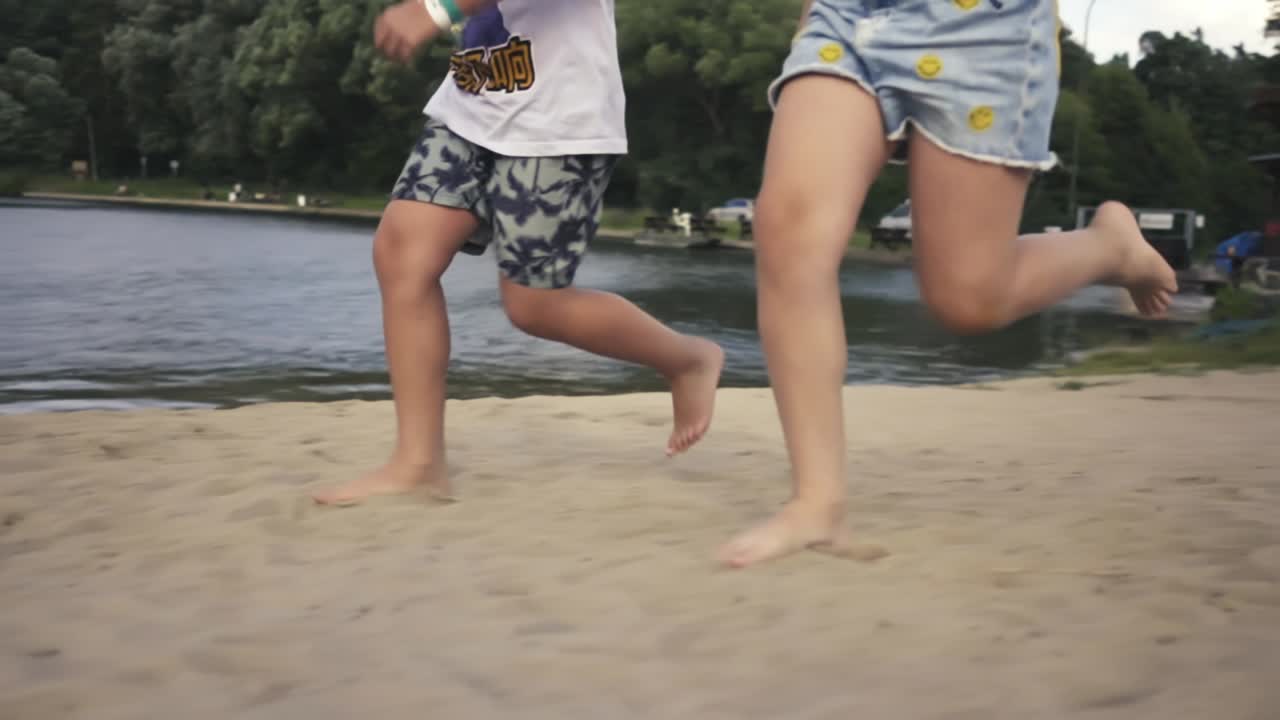 Bare feet of a girl and a boy running on the sandy beach around the lake