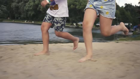 Bare-feet-of-a-girl-and-a-boy-running-on-the-sandy-beach-around-the-lake