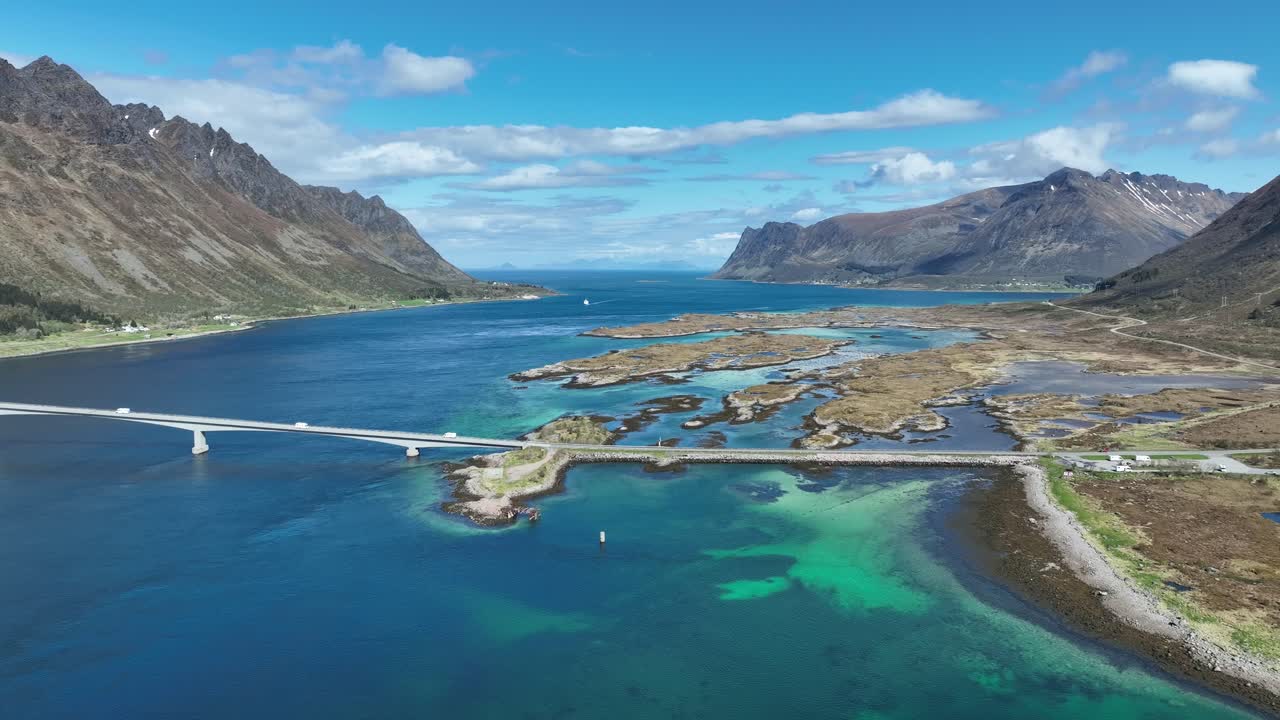 Aerial view of Gimsoy channel and bridge with islands, mountains, and turquoise water in spring