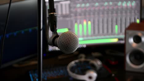 locked-off shot of a microphone in close up, with computer monitors in the background