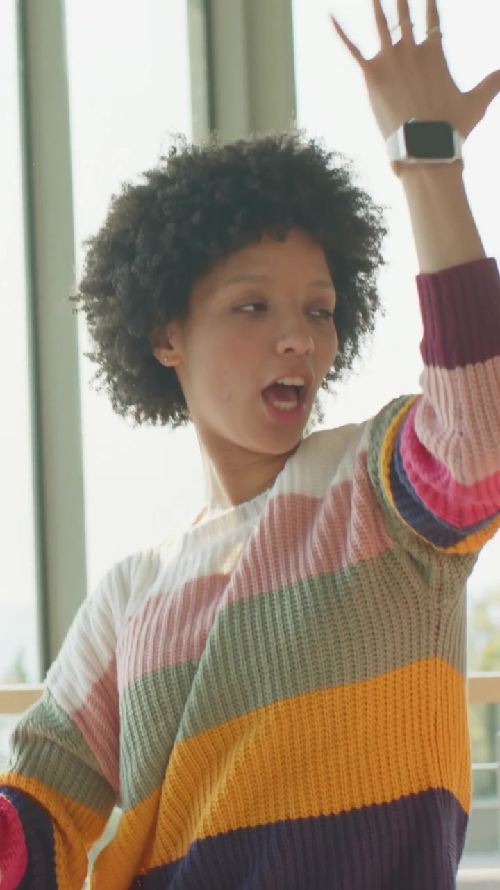Vertical video: Raising arms woman in sweater calling by balcony, friend holding gloss playing