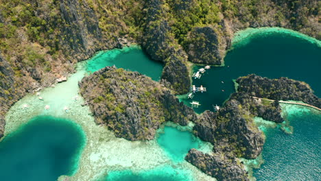 aerial shot tilting down to show outrigger boats on matinloc island, el nido, palawan, phillipines