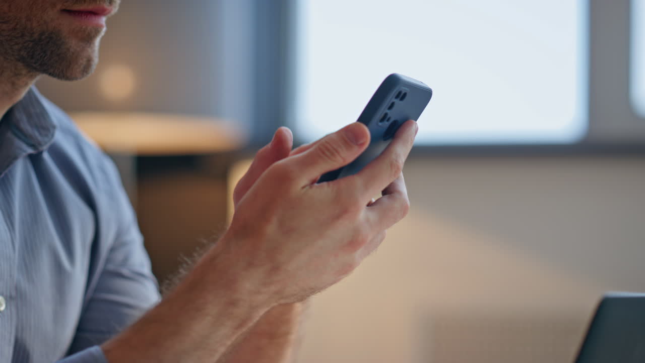 Closeup businessman fingers swiping telephone at modern office. Man browsing