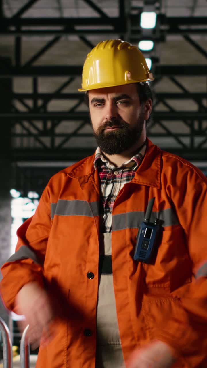 Video verticale. Ritratto di professionista uomo con elmetto che esamina la lavorazione dei metalli nel reparto di produzione.